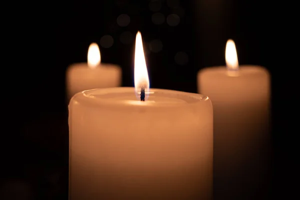 Bílá hořící svíčka stojí před tmavým pozadím — Stock fotografie