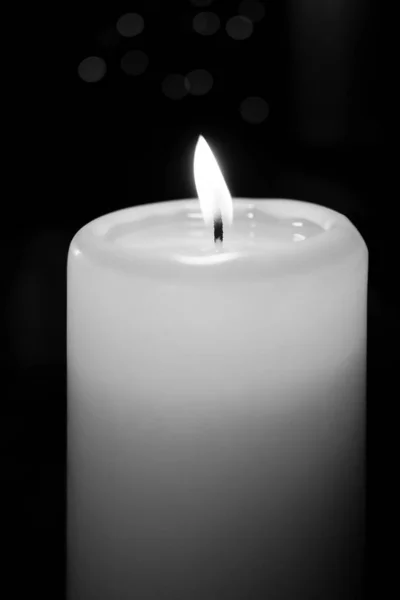 White burning candle stands before a dark background — Stock Photo, Image