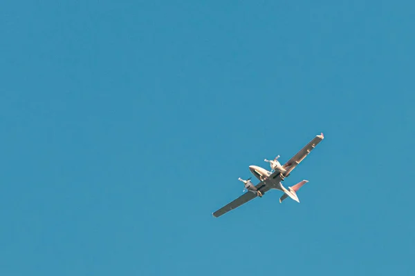 Dwusilnikowy mały samolot leci na niebieskim bezchmurnym niebie — Zdjęcie stockowe