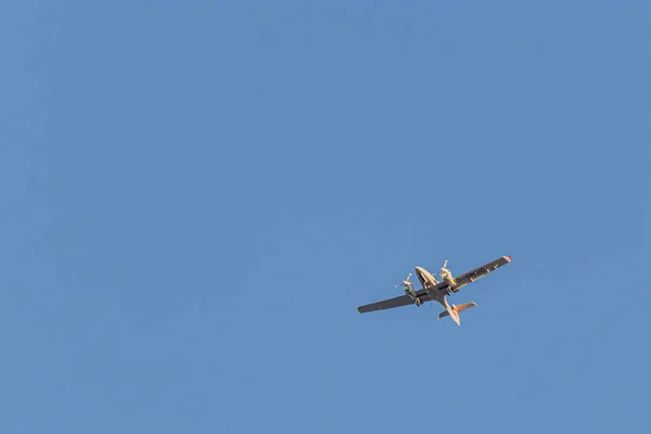 Een tweemotorig klein vliegtuig vliegt in de blauwe wolkenloze lucht — Stockfoto