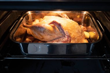 in an oven there is a roasting pot in which a raw duck lies to b