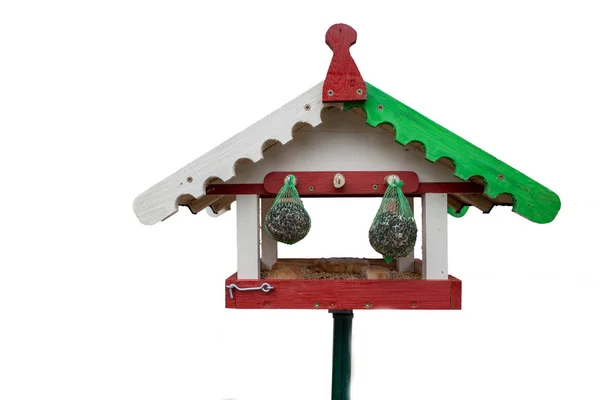 Птичий домик, выкрашенный в зеленый и красный цвета, стоит на фоне белого нарта — стоковое фото