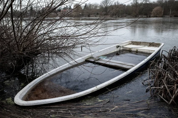 Затонувшая лодка лежит на берегу замерзшего небольшого озера — стоковое фото