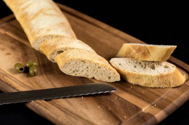 on a white wooden board lies sliced bread and beside it lies a k