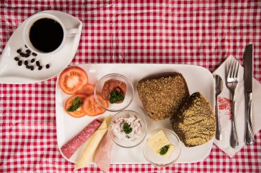 on a red chequered tablecloth is a plate with a hearty breakfast