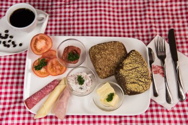 on a red chequered tablecloth is a plate with a hearty breakfast