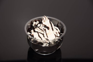 a sundae with vanilla ice cream and sauce on a dark base