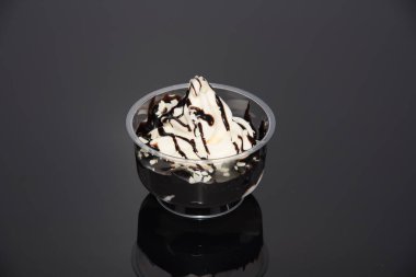 a sundae with vanilla ice cream and sauce on a dark base