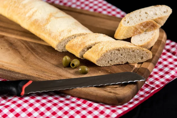 Sobre un tablero blanco de madera se encuentra el pan en rodajas y al lado de él se encuentra una k — Foto de Stock