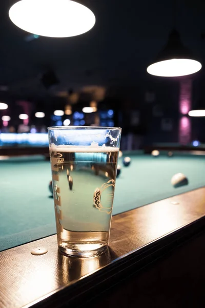 In a billiard parlor on the rail of a pool table is a glass with — 스톡 사진