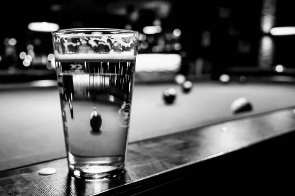 In a billiard parlor on the rail of a pool table is a glass with — 스톡 사진