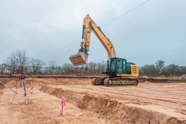  Orada bir inşaat alanı var. Sarı bir kazıcı, orfozu hazırlıyor.