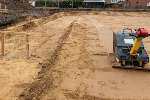 Un sitio de construcción hay un vibrador preparando el terreno para fo —  Fotos de Stock