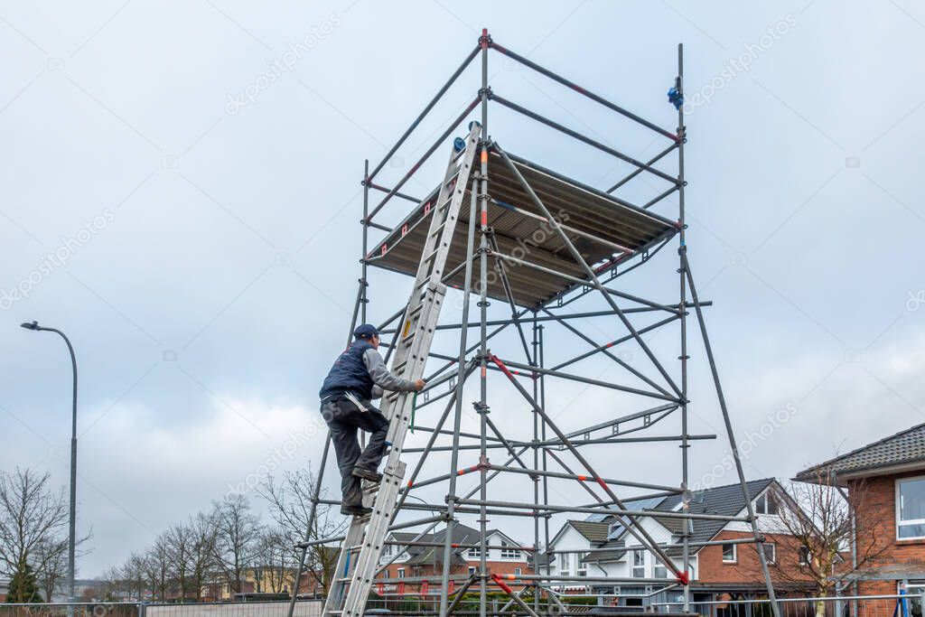 man climbs onto scaffolding on an extension ladder