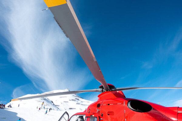 a red rescue helicopter stands on the snow-covered mountains of the Austrian Alps