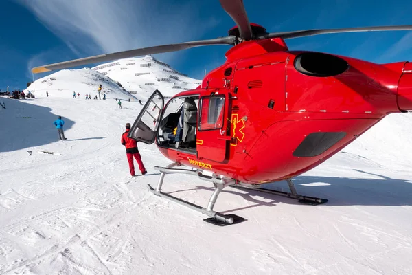 オーストリアアルプスの雪に覆われた山の上に赤い救助ヘリコプターが立っています — ストック写真