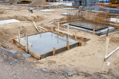 Bir fabrika binasının sütunlarının beton temelleri büyük bir inşaat sahasına dökülüyor.