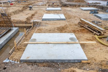 Bir fabrika binasının sütunlarının beton temelleri büyük bir inşaat sahasına dökülüyor.