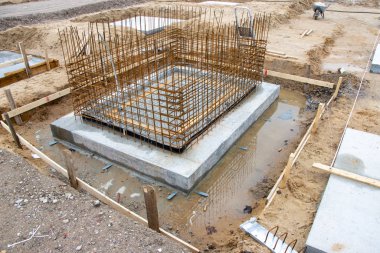 Bir fabrika binasının sütunlarının beton temelleri büyük bir inşaat sahasına dökülüyor.