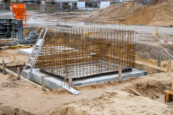 The concrete foundations for the columns of a factory building are poured on a large construction site