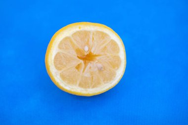 Kesilmiş sulu bir limon mavi bir arka planda yatıyor.