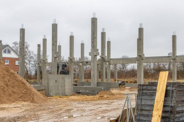 Büyük bir inşaat sahasına birçok beton kolon bir vinç yardımıyla yerleştirilir.