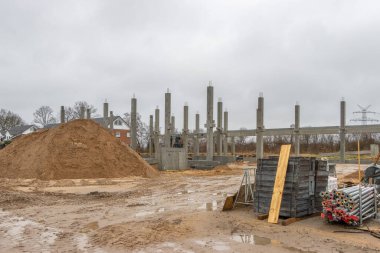 Büyük bir inşaat sahasına birçok beton kolon bir vinç yardımıyla yerleştirilir.