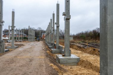 Büyük bir inşaat sahasına birçok beton kolon bir vinç yardımıyla yerleştirilir.