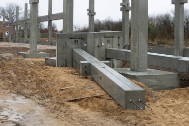 Büyük bir inşaat sahasına birçok beton kolon bir vinç yardımıyla yerleştirilir.