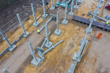 Büyük bir inşaat sahasına vinç kullanılarak büyük beton sütunlar inşa edilir.