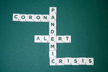 Yeşil zeminde harflerle yazılmış oyun taşları vardır: Corona, salgın, alarm, kriz.
