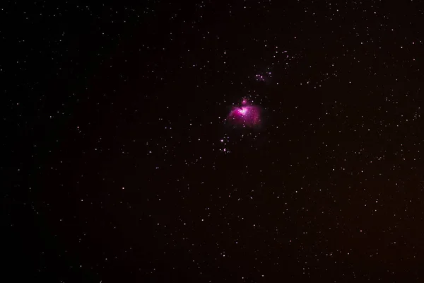 the pink Orion Nebula in the starry night sky