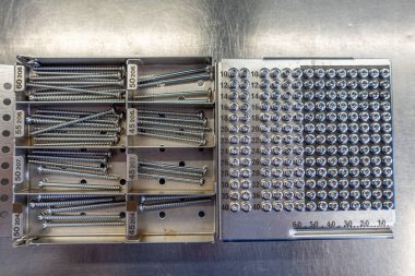 Ameliyat masasında çeşitli cerrahi çelik vidalarla dolu bir tepsi var.