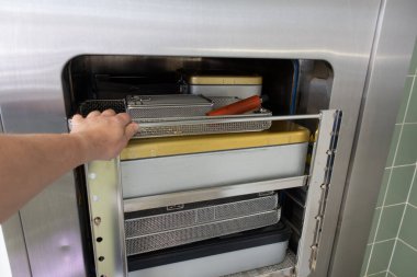 Cerrahi aletlerle dolu bir araba sterilizatöre itilir.