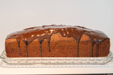 Çikolata kremalı kahverengi pasta cam bir tabakta duruyor. 