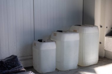 Bir atölyenin duvarında duran üç farklı boyutta beyaz teneke kutu.