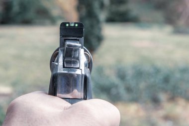 Bir sol el havada büyük gümüş bir tabanca tutuyor.