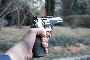 Bir sol el havada büyük gümüş bir tabanca tutuyor.