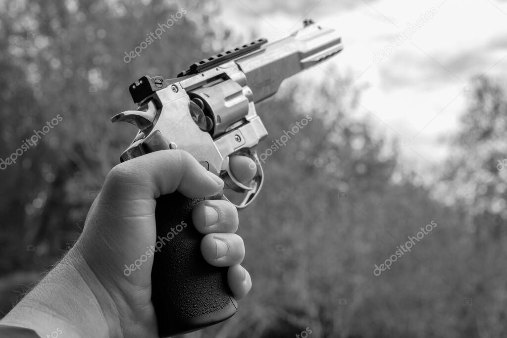 a left hand holds a big silver revolver in the air