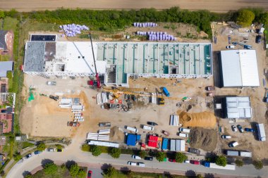 Büyük bir fabrika binasının inşa edildiği büyük bir inşaat alanının insansız hava aracı fotoğrafı.