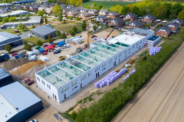 a drone photograph of a large construction site on which a large factory hall is being built