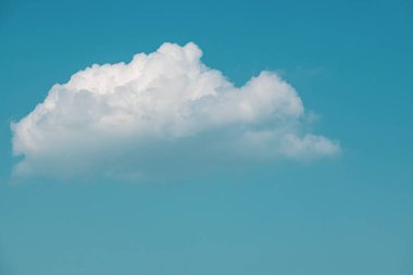 Mavi gökyüzünde tek bir beyaz kuzu bulutu var.