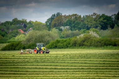 ein Bauer wendet das Heu auf einem Feld mit see Traktor