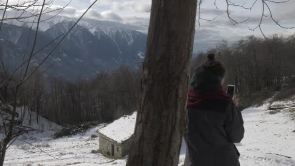 Dívka fotografování panorama v horách v zimě, sledování výstřel — Stock video