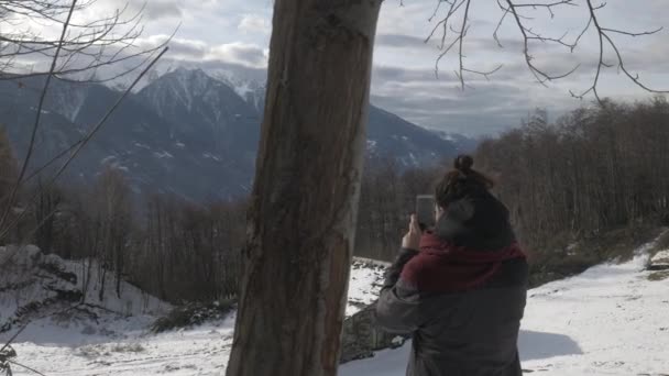 Κορίτσι λήψη μια πανοραμική φωτογραφία στα βουνά το χειμώνα, tracking shot — Αρχείο Βίντεο