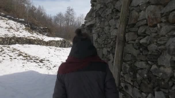 Flicka gå förbi en stuga i snön vidrör dess väggar — Stockvideo