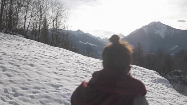 Menina andando em uma colina nevada para o pôr do sol, tiro de rastreamento estabilizado — Vídeo de Stock