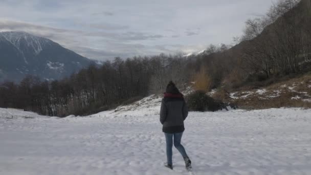 Паралакс знімок дівчини, що йде в сніжному пейзажі в горах — стокове відео