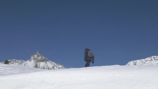 Climber hiking on a snowy ridge towards a mountain — 비디오