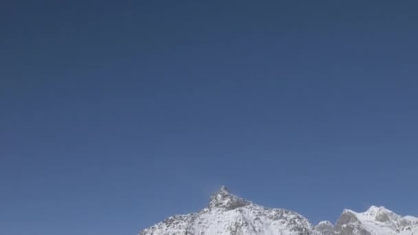Revealing tilt shot of a hiker walking in a snow field in the alps — 비디오